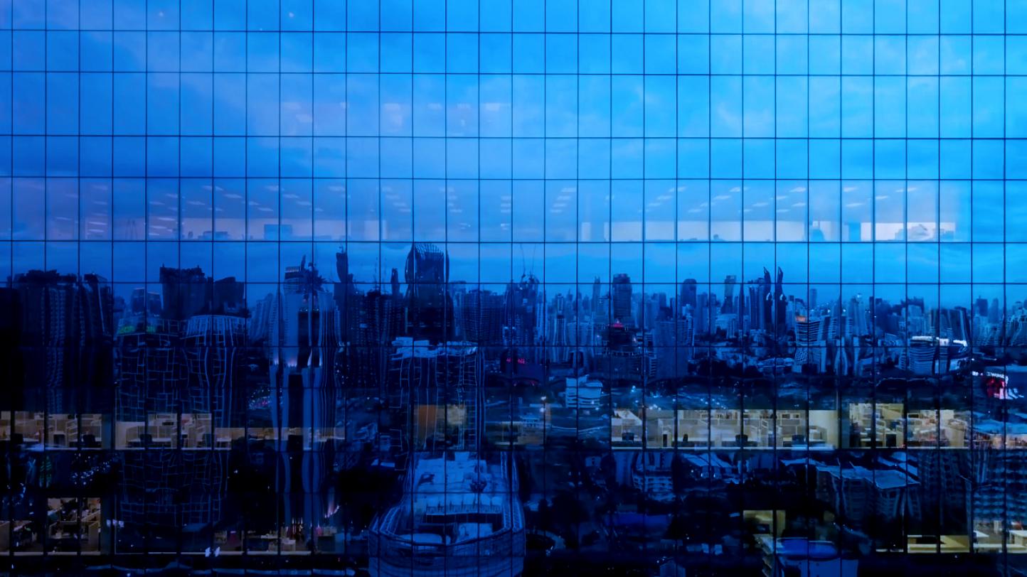 A cityscape as seen through the reflection on a building.
