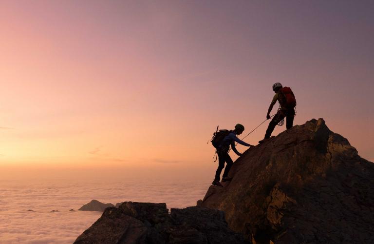 Image of two mountain climbers and a sunset.