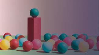 A green sphere stands on top of a pedestal surrounded by a crowd of multicoloured spheres